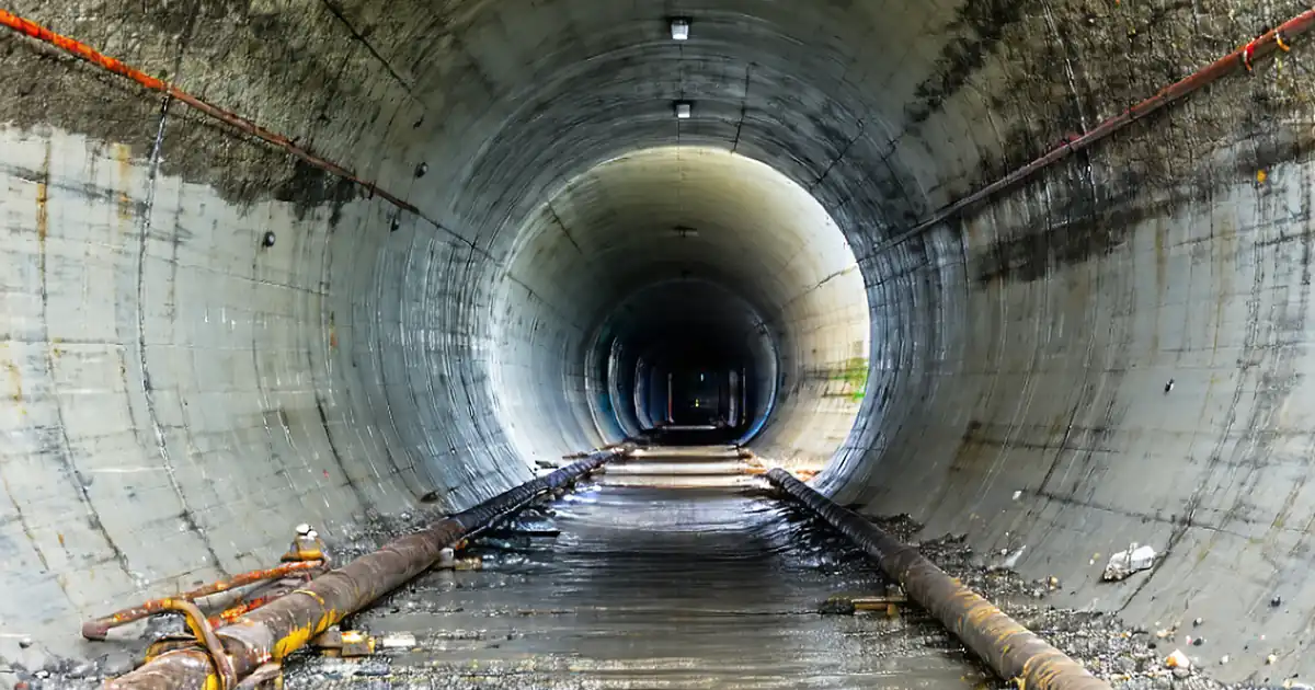 Photo-realistic editorial image of a civil construction crew testing a sanitary sewer segment at a manhole: pneumatic plugs with hoses and gauges, engineer pulling a mandrel, CCTV crawler and service van with monitor, traffic cones and barricades, urban right-of-way setting, early morning side-lighting, crisp details, 16:9 composition, no text image